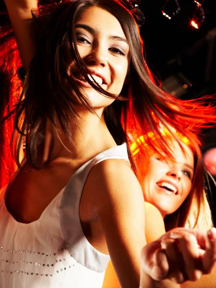 Image of energetic girl looking at camera while dancing on background of her friends